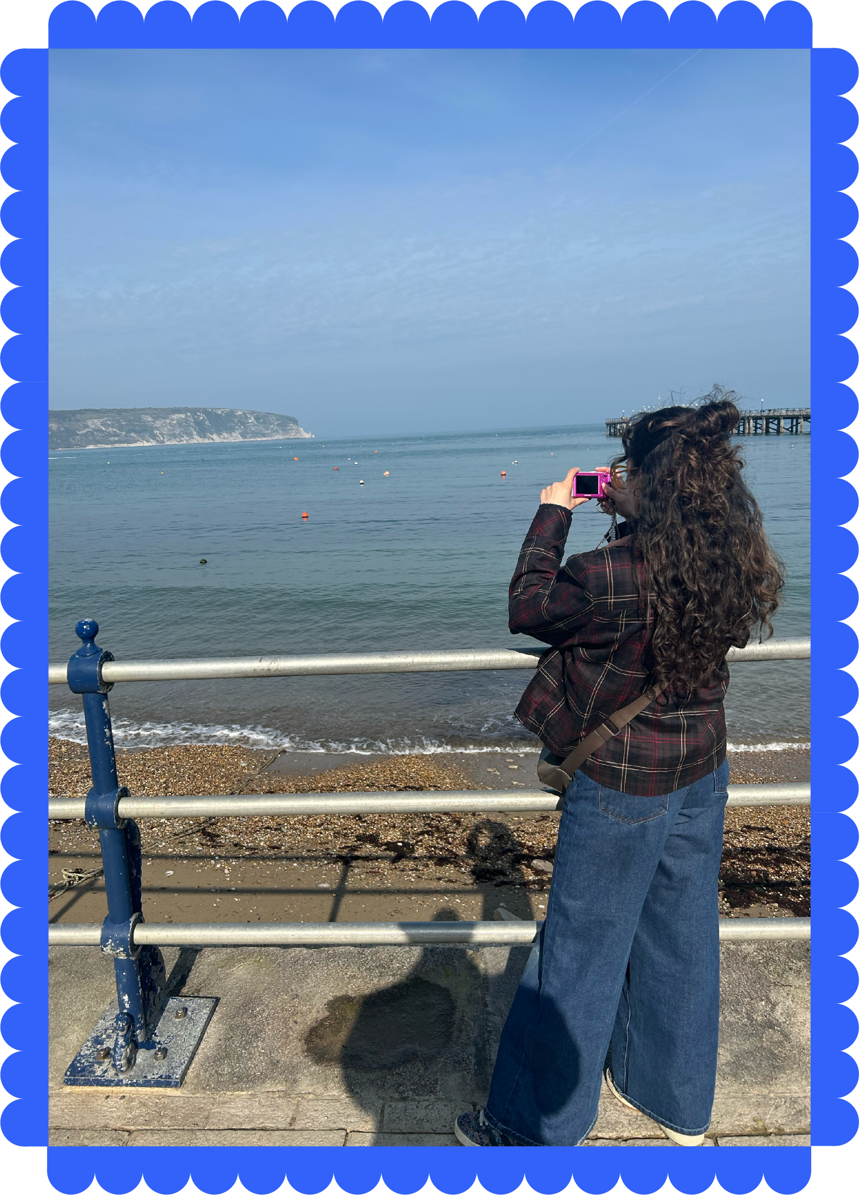 Millie taking a photo by the sea